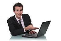 Siedzący biznesman pokazuje dłonią na ekran laptopa